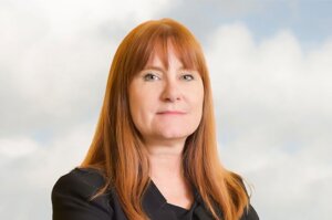 Eve Hill stands in front of cloud background.