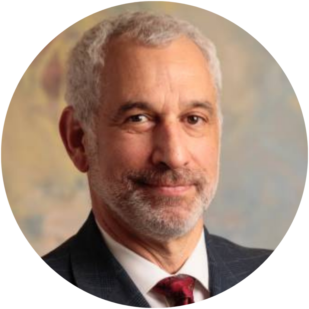 Andy Freeman headshot. Andy is wearing a black suit, white shirt and red tie. He is white with short grey hair and a short salt-and-pepper beard.