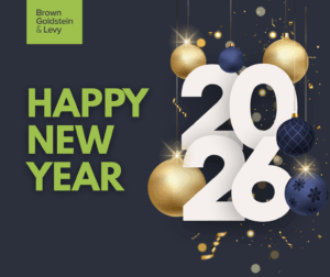 Image reads "HAPPY NEW YEAR" in bold light green text on a dark navy blue background alongside large white numbers reading "2026". The numbers are decorated with hanging gold and navy blue ornaments and festive sparkles and confetti in various shades of gold and silver. There is a  green logo that reads "Brown Goldstein & Levy" in dark gray font in the top left corner.