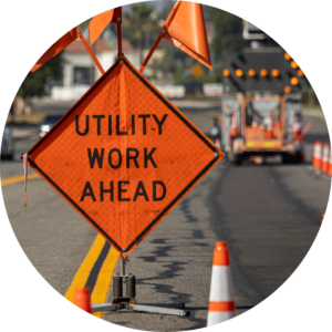 Orange hazard sign on road says "Utility work ahead"